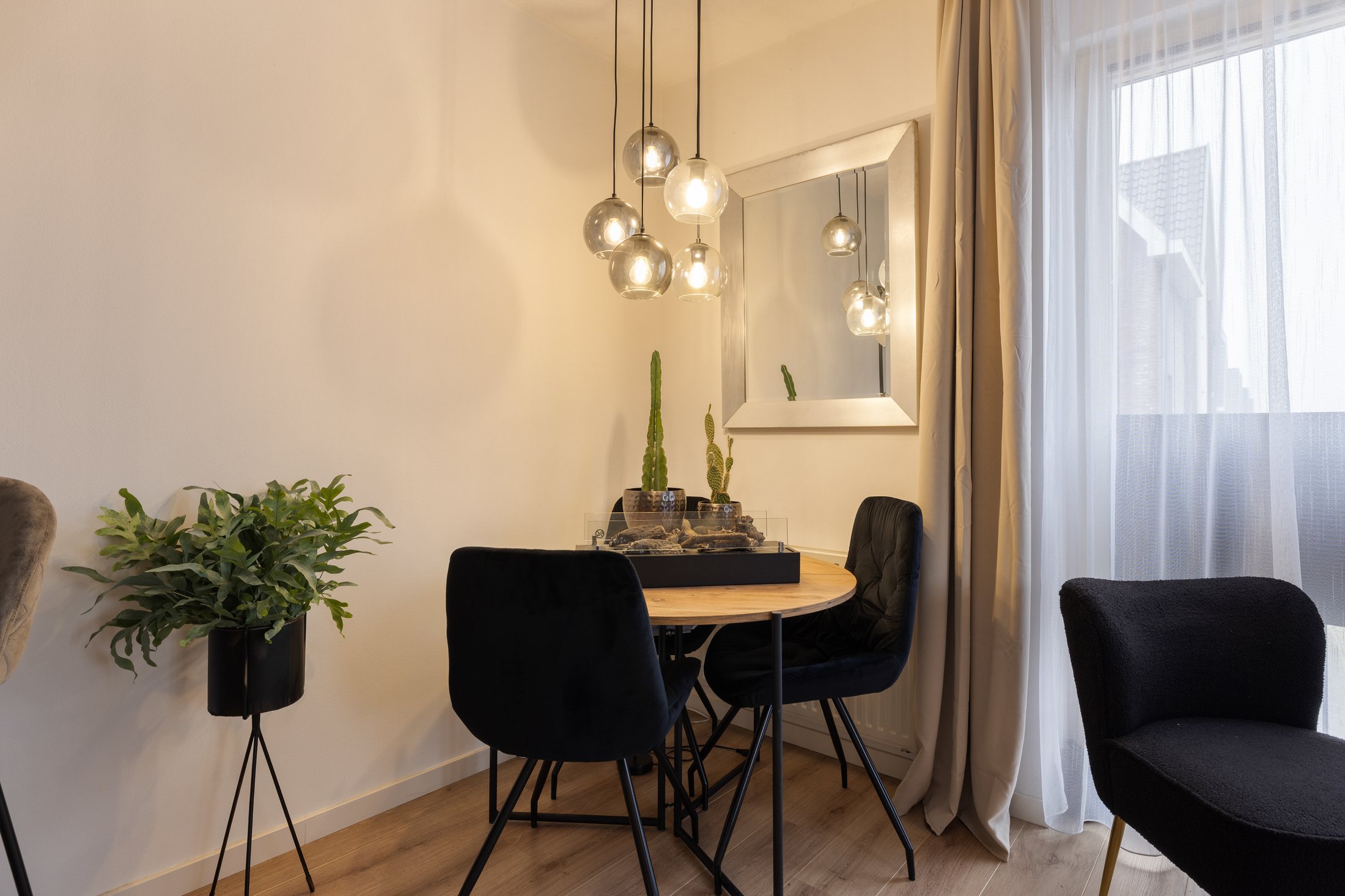 Eethoek met ronde tafel, zwarte stoelen en zachte verlichting