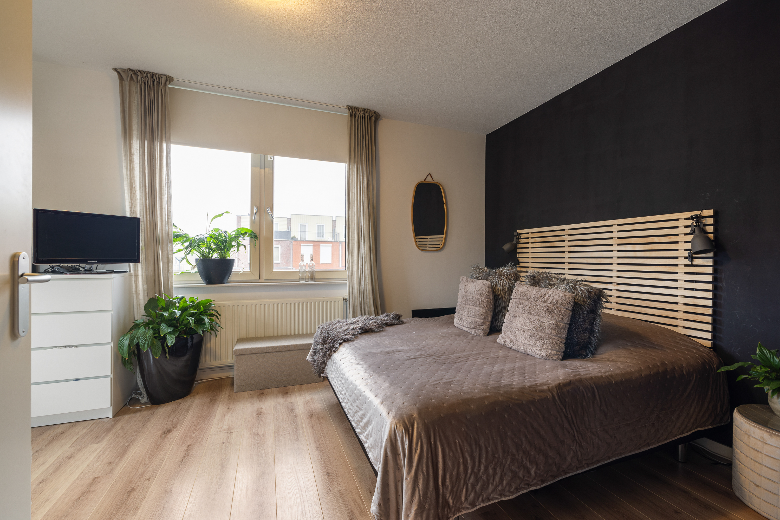 Slaapkamer met donkere accentwand en warm bedtextiel