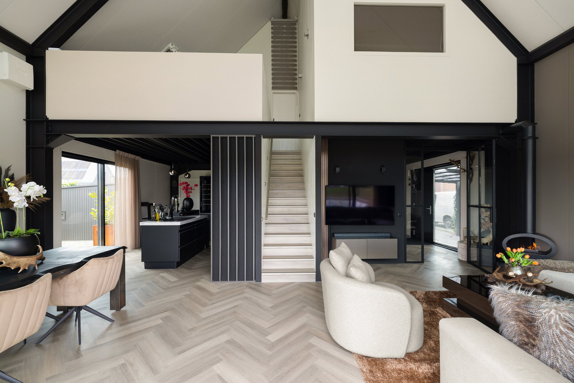 Open leefruimte met hoog plafond, zithoek en zicht naar buiten